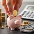 Mână, monede, pușculiță, calculator, creștere financiară.